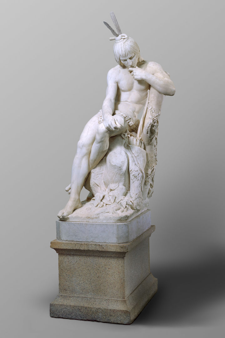 A white marble sculpture of an Indigenous man, seated with his head in his hands as if thinking