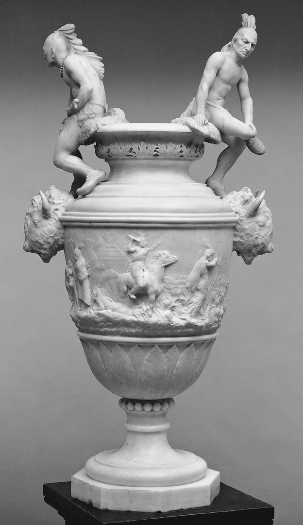 A large white vase decorated with bison and Indigenous figures