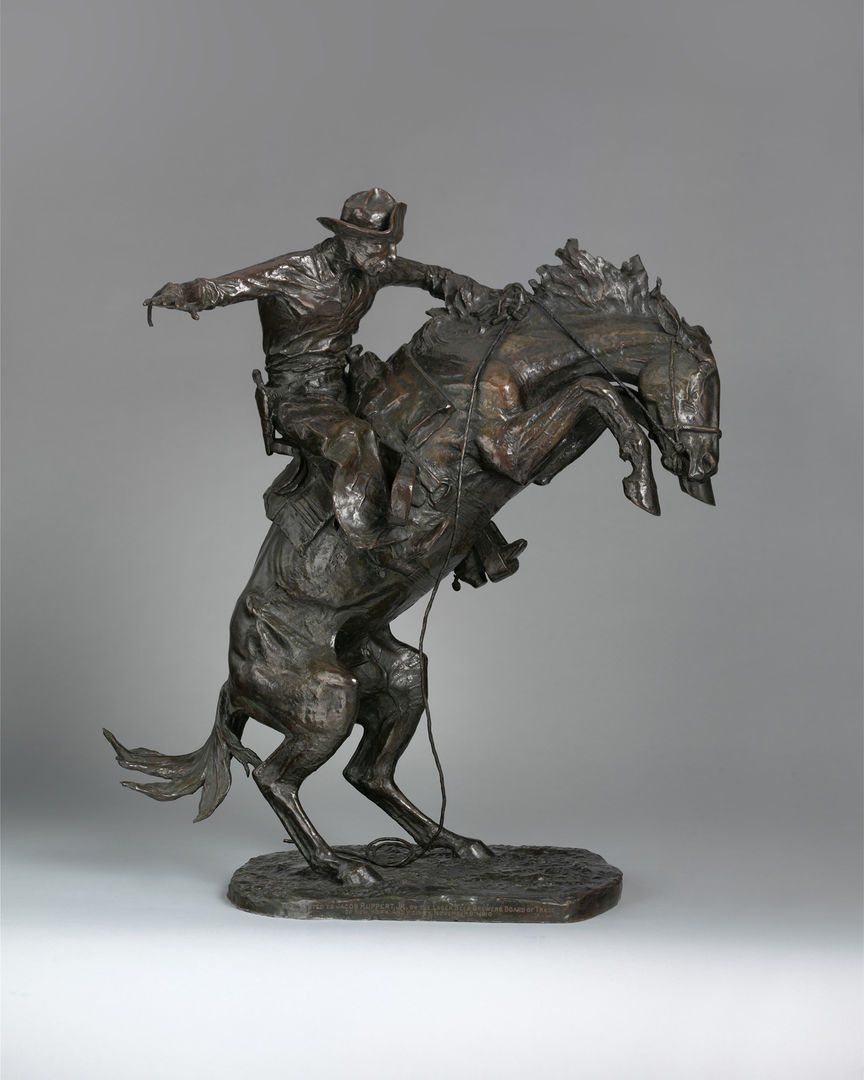A bronze sculpture of a cowboy riding a bucking bronco