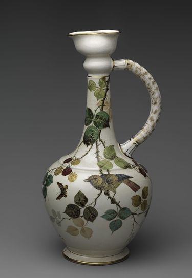 An earthenware ceramic ewer decorated with images of birds, insects, branches, and leaves