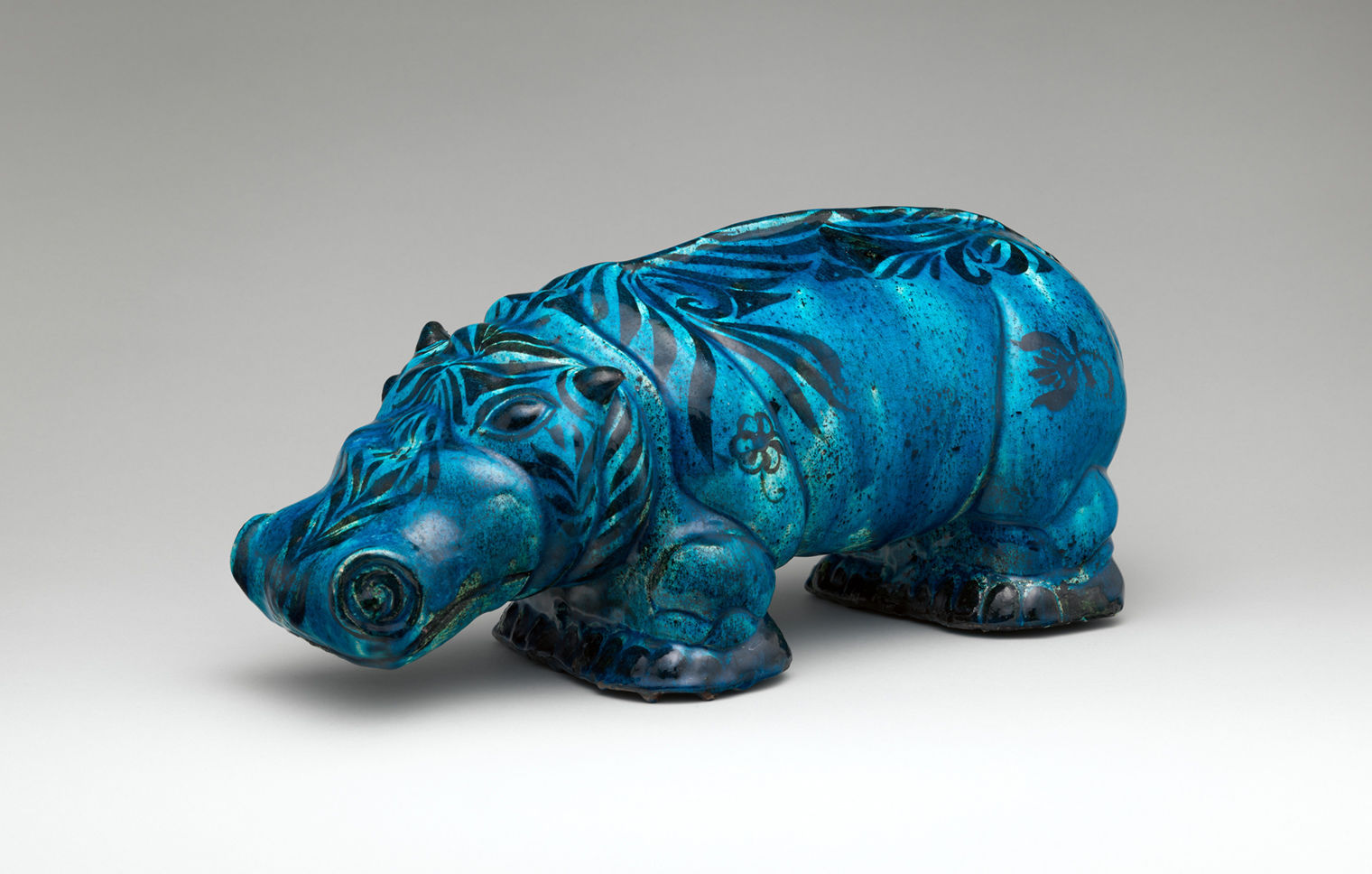 A blue ceramic hippo with dark blue markings, facing left