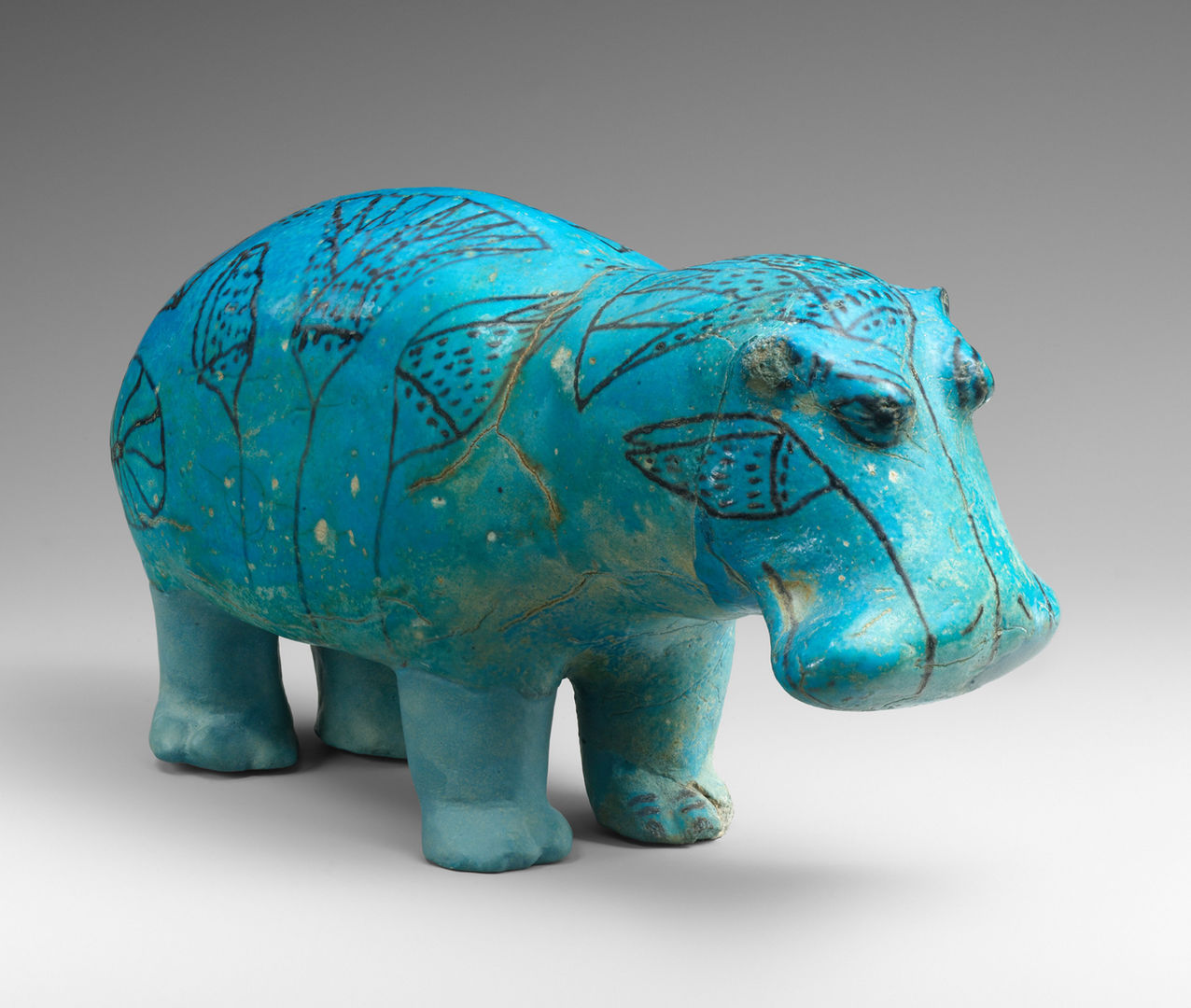 A blue ceramic hippo with dark markings, facing right.