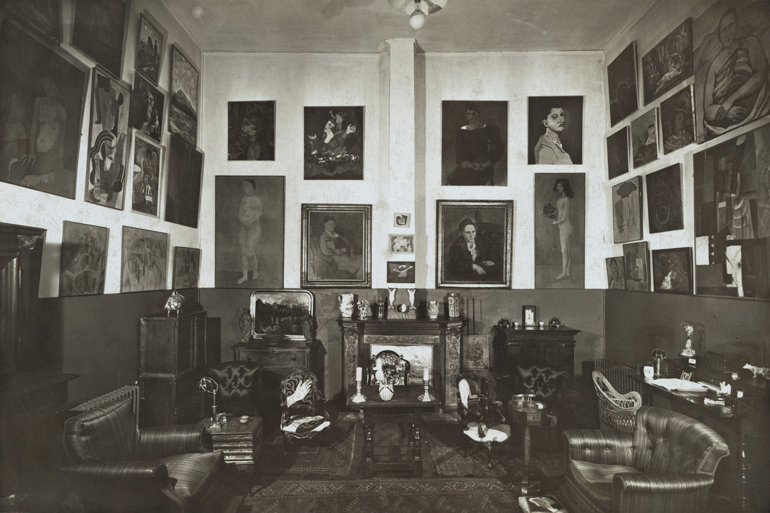 A black-and-white photo of a large salon filled with paintings