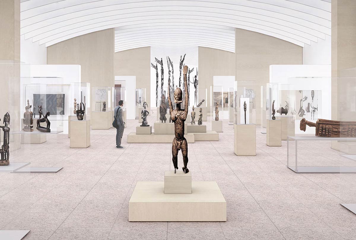 Pale wooden stands with wooden figurines stand in a brightly lit large gallery with transparent ceilings