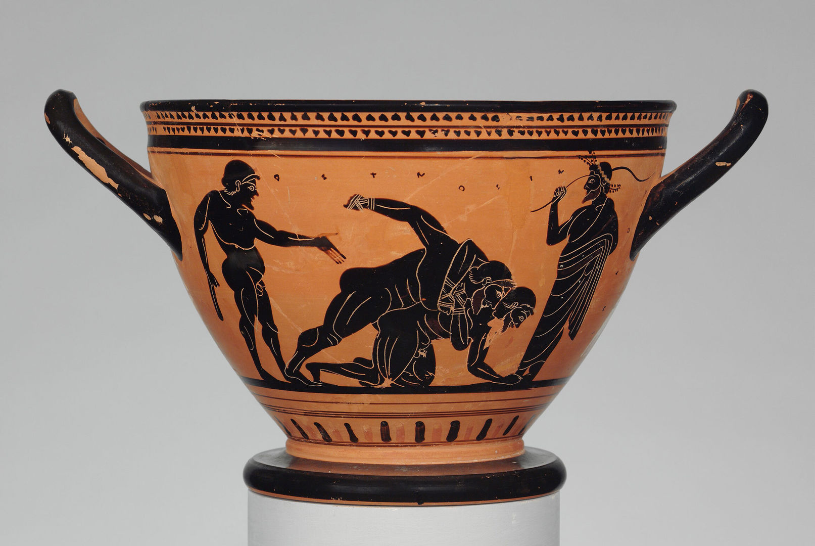 A terracotta vessel depicting two men wrestling