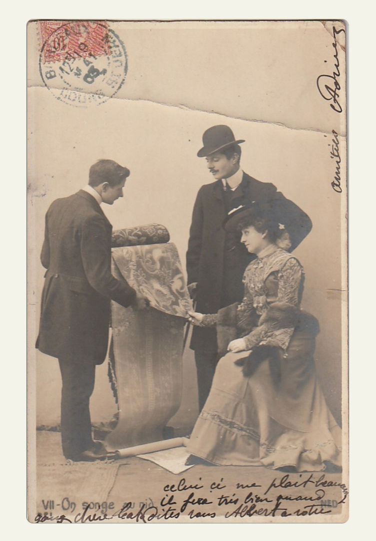 Black and white photograph on a postcard of a man showing a printed fabric to a couple