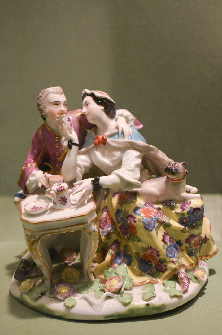Porcelain couple drinking tea and smiling, the woman offers a cup to the man