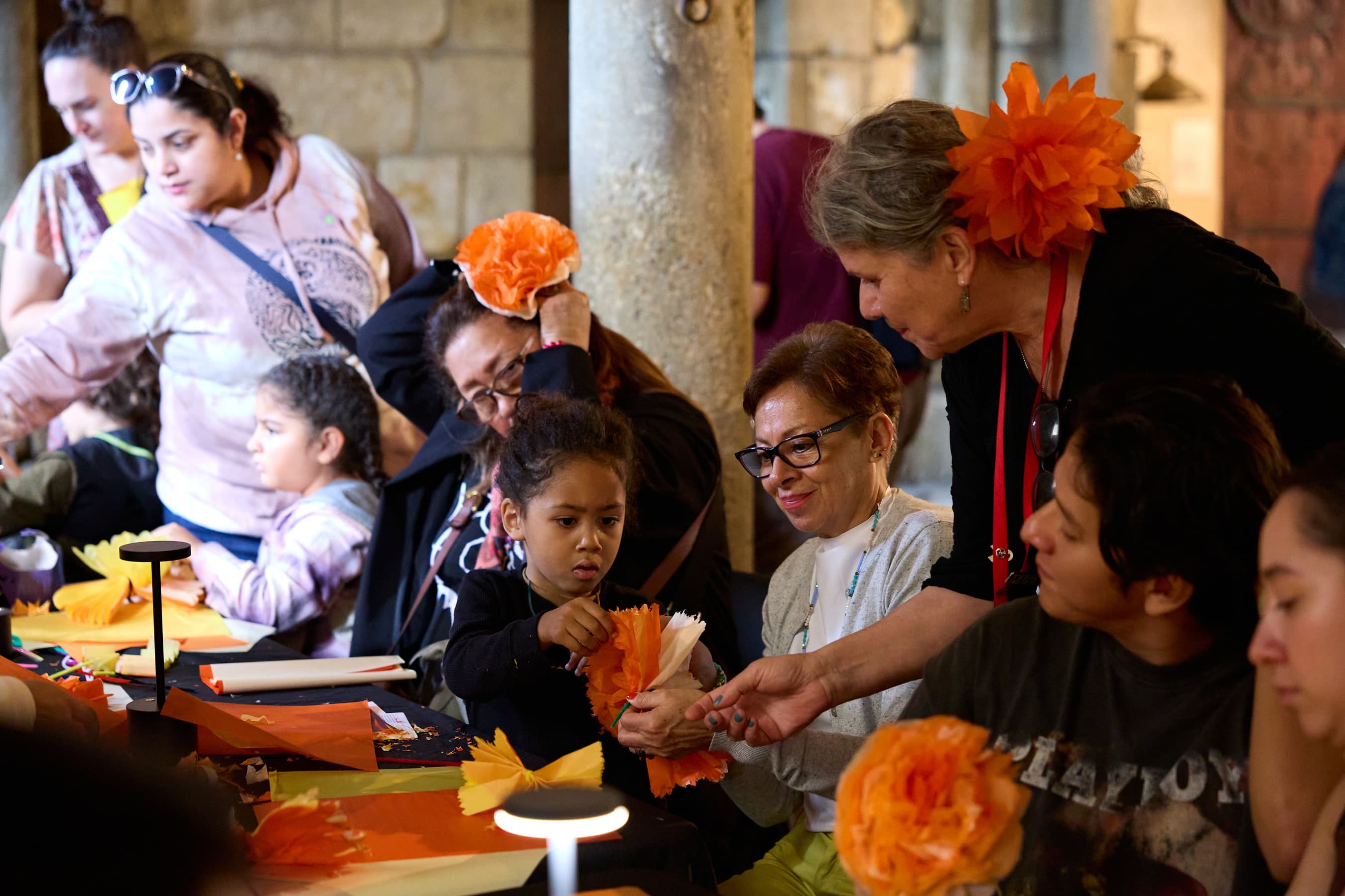 A child and a woman folding paper into flowers with an educator