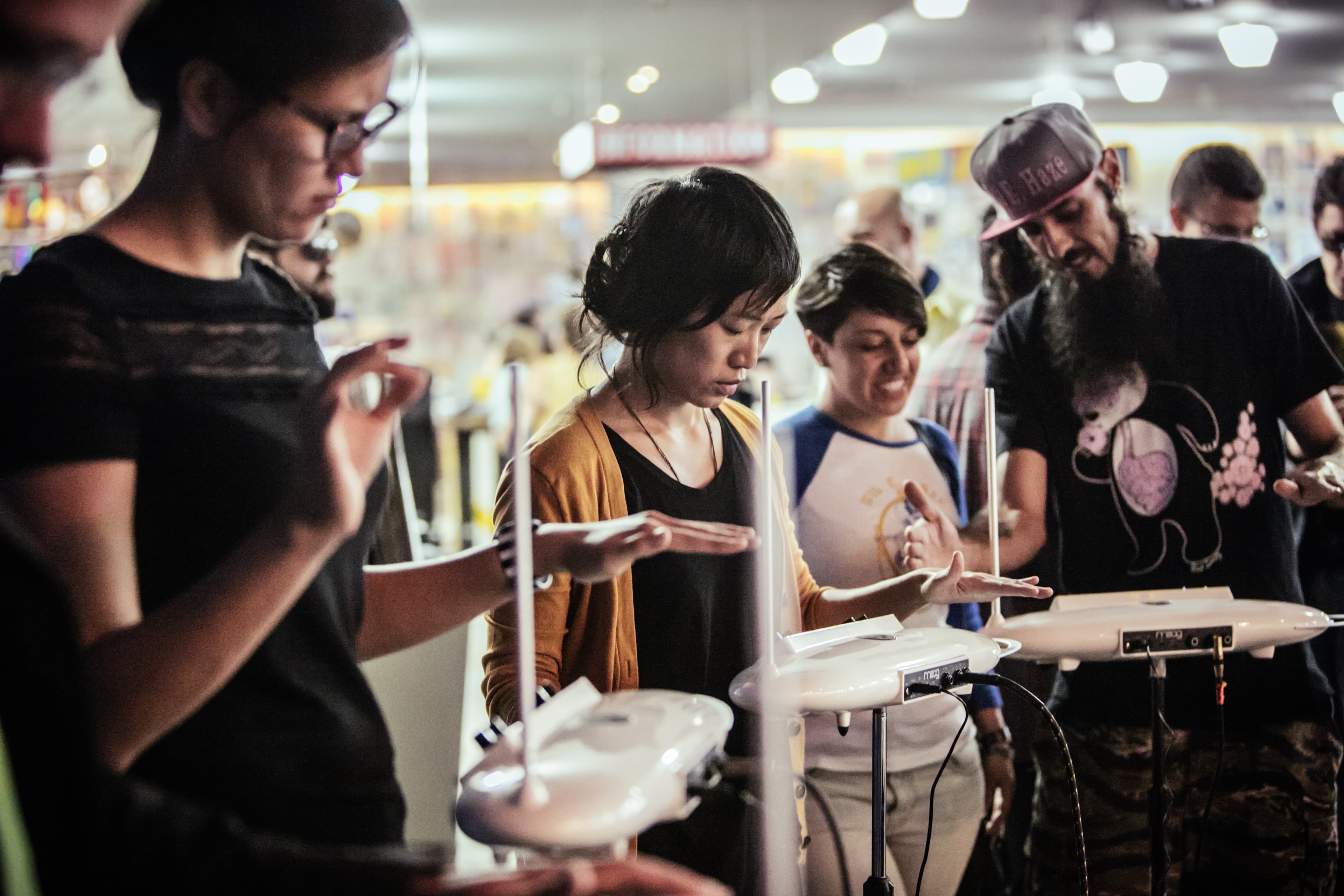 4 people standing in front of theremins learning to play.