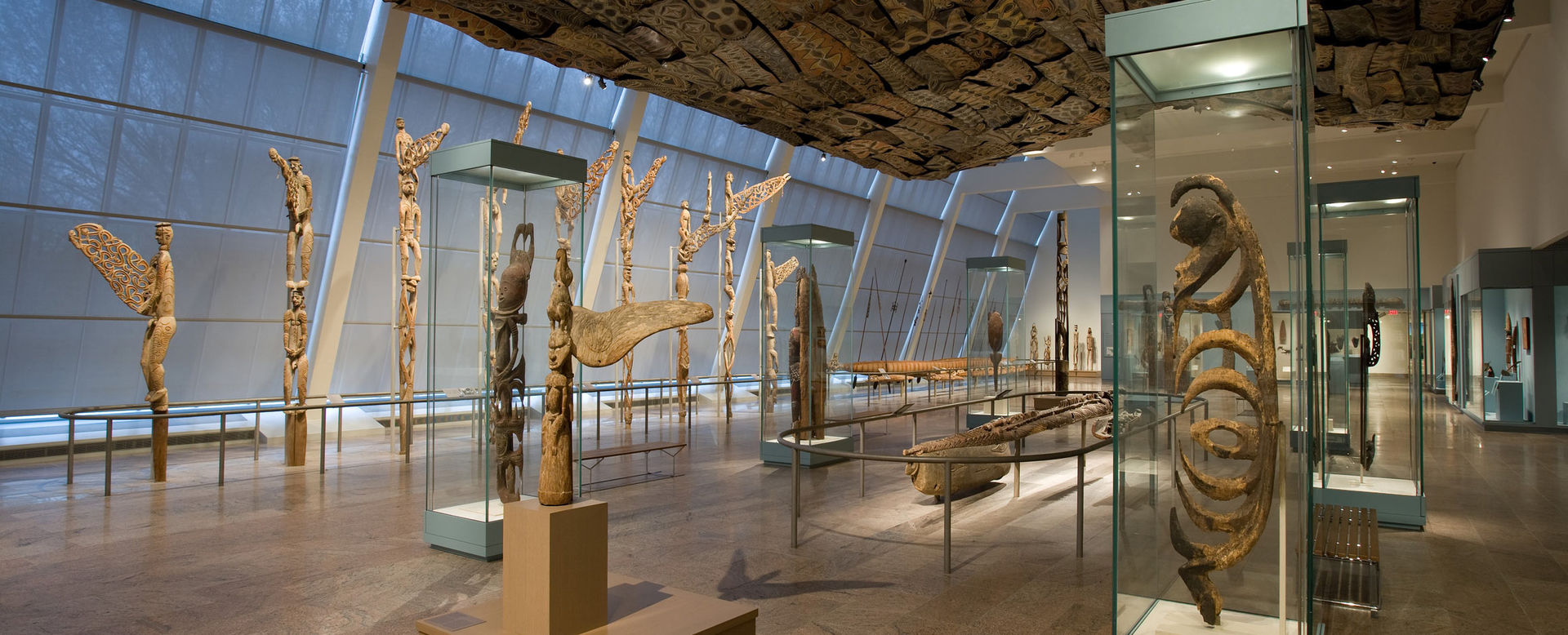 A glass-enclosed gallery with wooden sculptures from Oceania