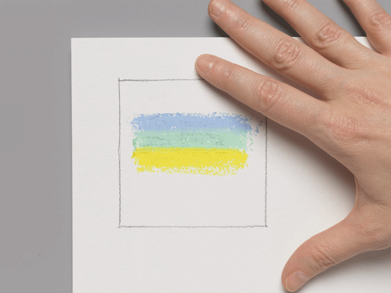 A moving image of a hand smudging lines of yellow, green, and blue pastel markings with their index finger.