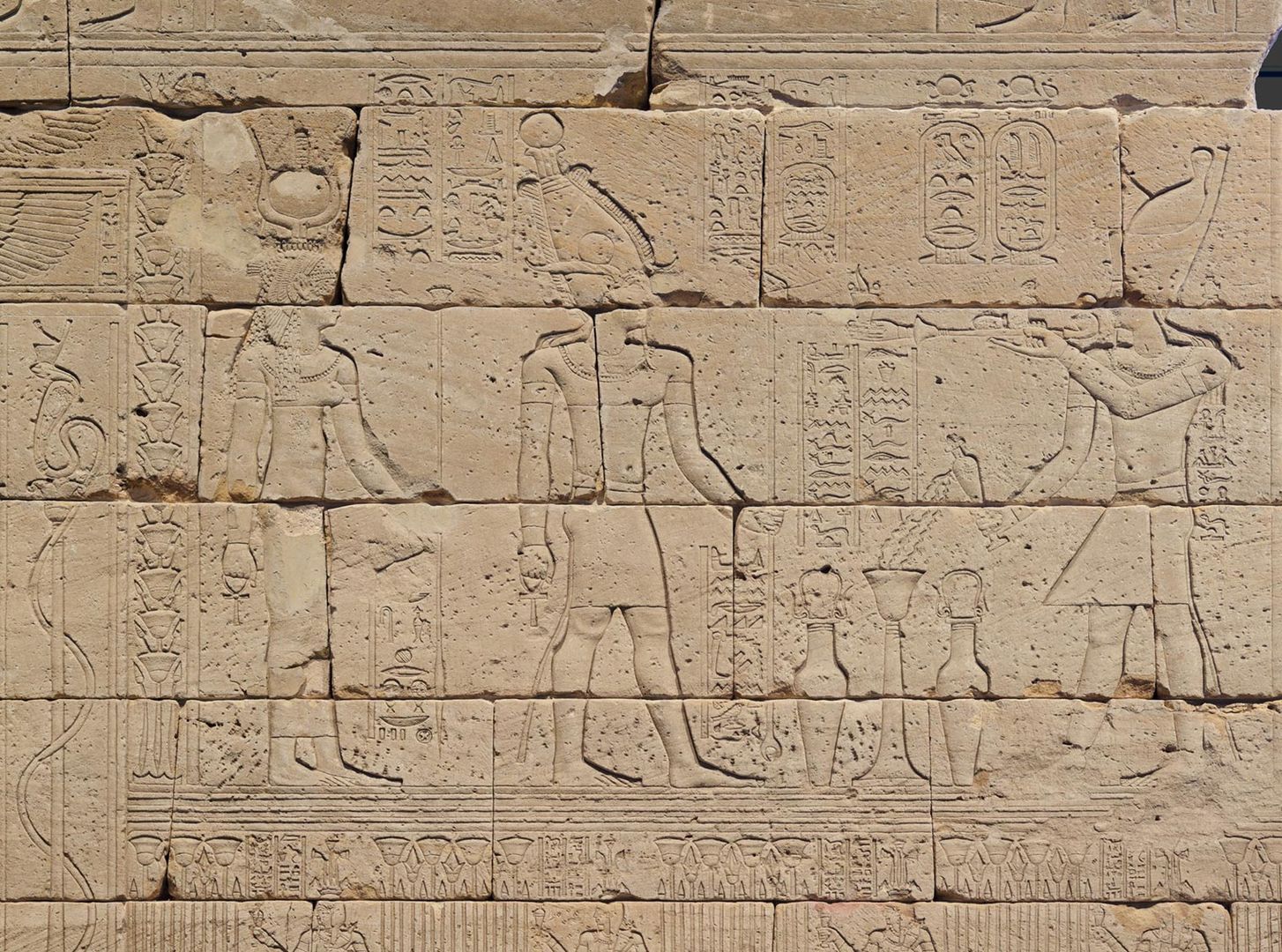 Detail of temple wall depicting Augustus (right) burning incense and pouring milk for the god Osiris (center) and the goddess Isis (left)