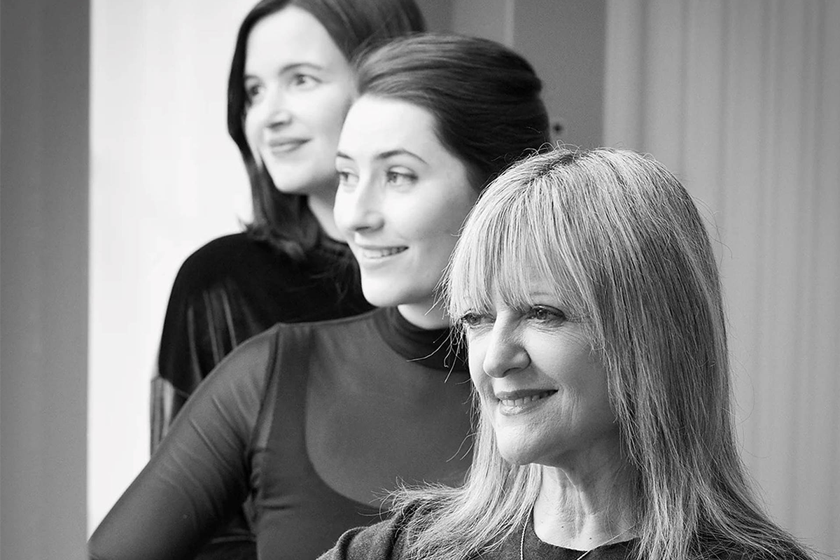 Three women who make up ModernMedieval photographed looking to the left and smiling in black and white.