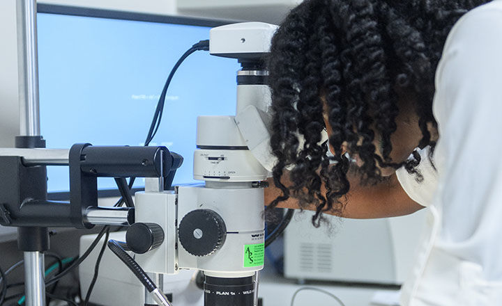 Two women in a lab closely examining and discussing a glass object 