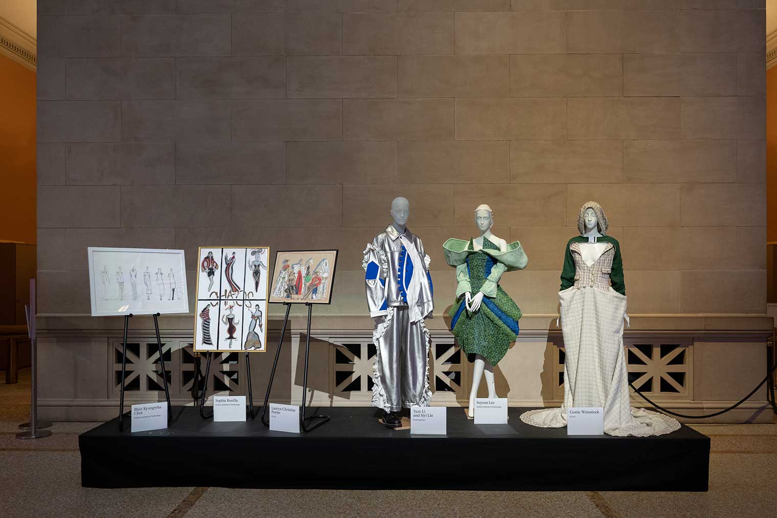 Several mannequins sporting fashions designs are displayed on a raised platform.