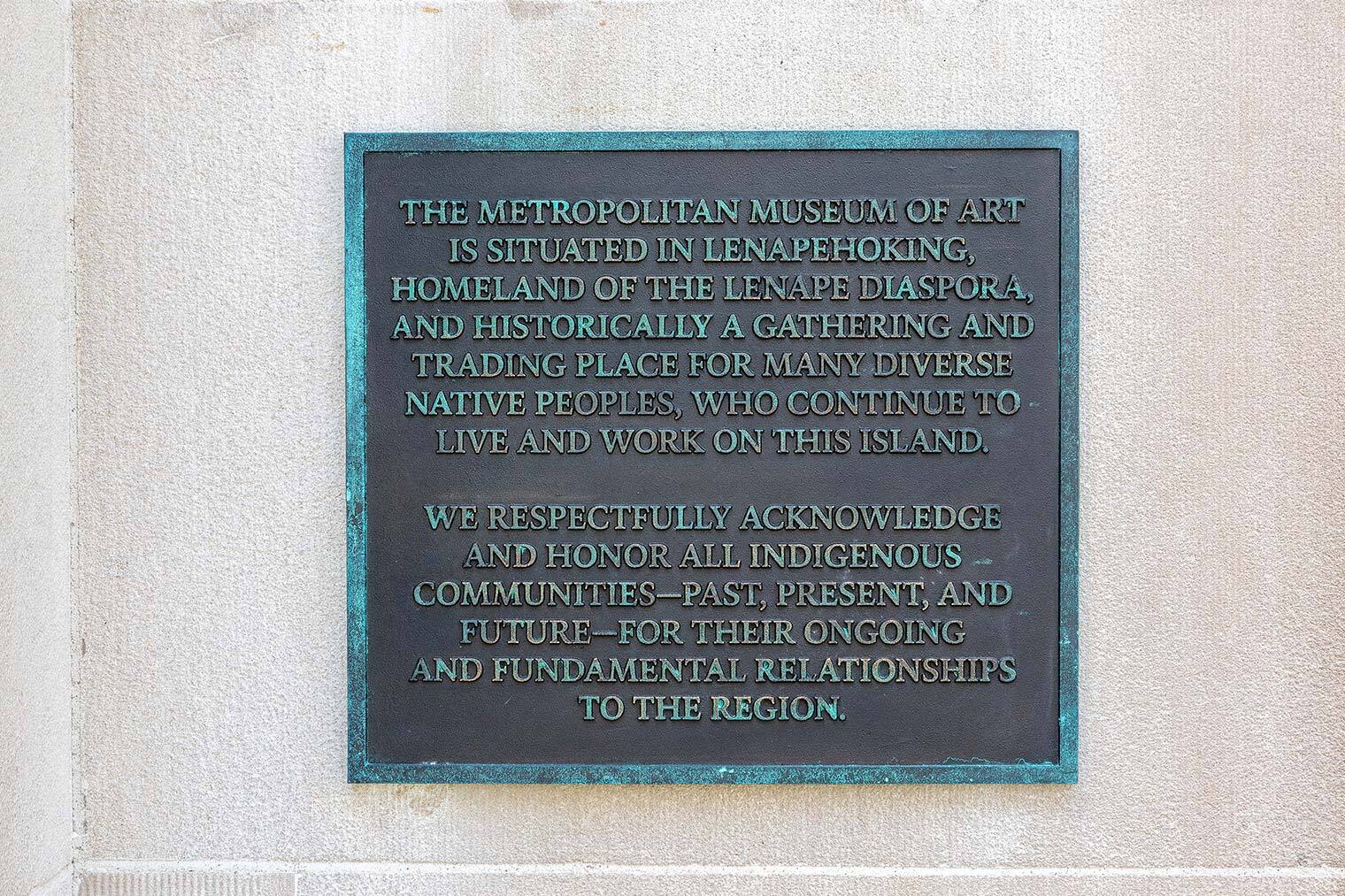 A bronze plaque mounted on the facade of The Met