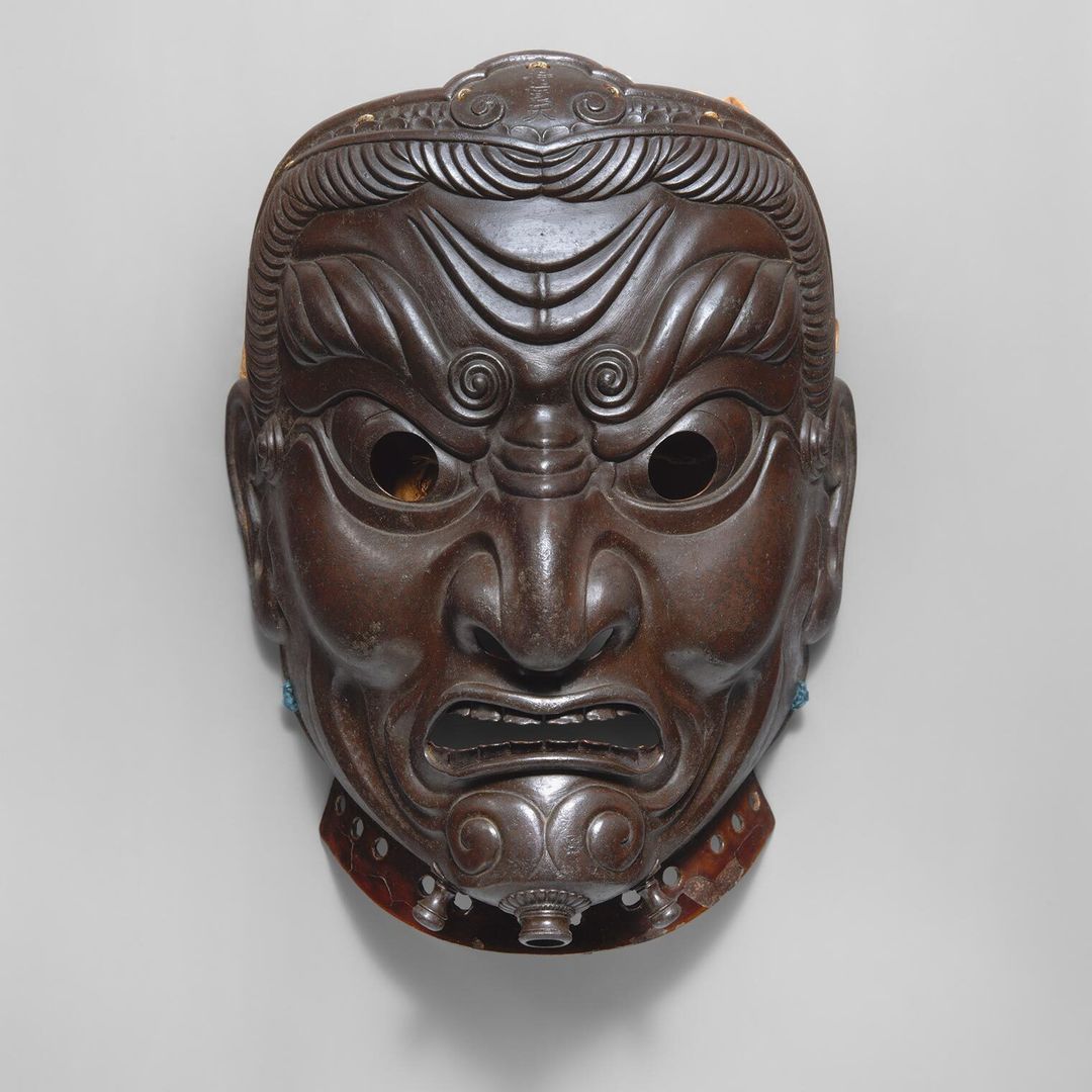 A metal mask depicting a fierce scowling god