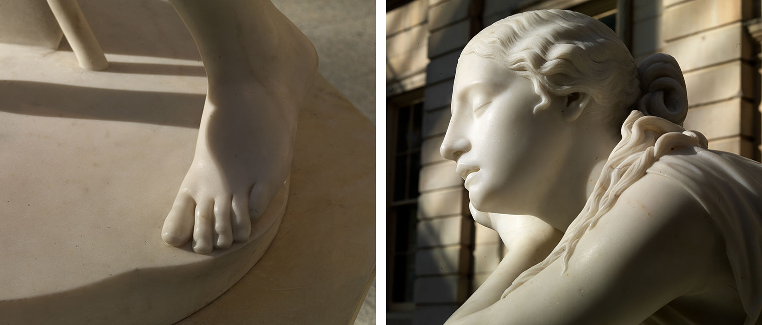 A diptych image divided by white space in the middle: On the left is a close-up shot of Nydia’s slightly raised white marble back left foot in dramatic lighting at the edge of the round base of the sculpture. On the right is a profile close-up shot of Nydia taken from the left side that is illuminated by the sun highlighting the smooth white marble of the sculpture and the hair flowing over her left shoulder and arm. 