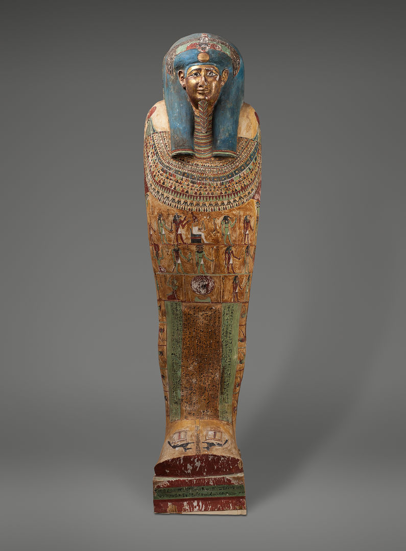 Elaborately decorated wooden Egyptian coffin. The figure represented wears a blue headdress and dramatic collar. Painted scenes cover the torso area, and hieroglyphics mark the lower part of the coffin.
