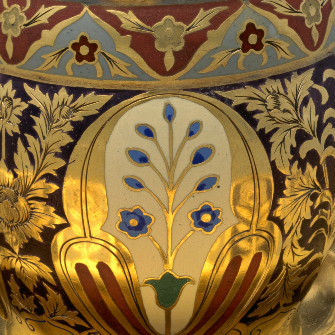 A close up detail of a highly reflective gilded and enameled cup adorned with floral motives set within geometric patterns.