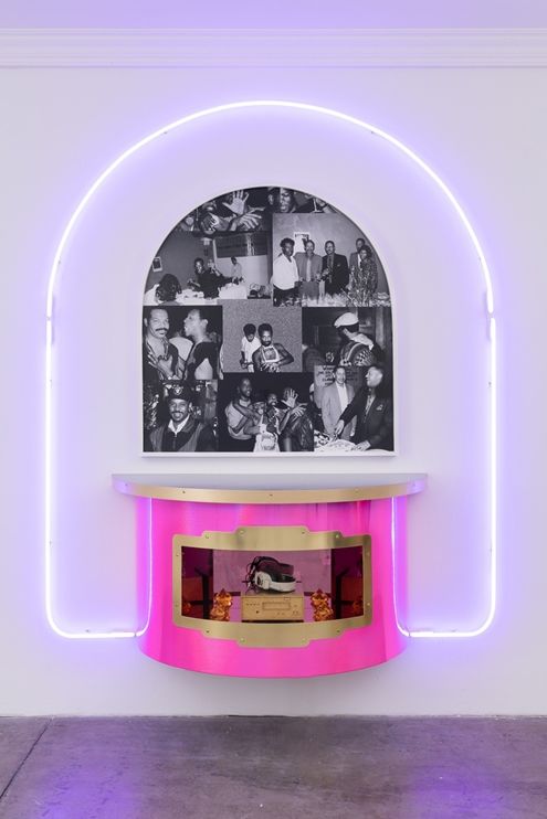 A sculpture of a neon-colored jukebox console with high contrast photographs in an arch in the center