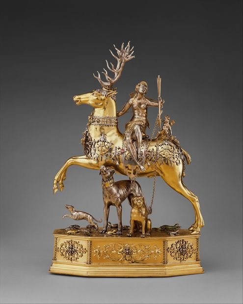 A golden statue of a deer ornamented with armor being ridden by a goddess with a bow and arrow in her hand