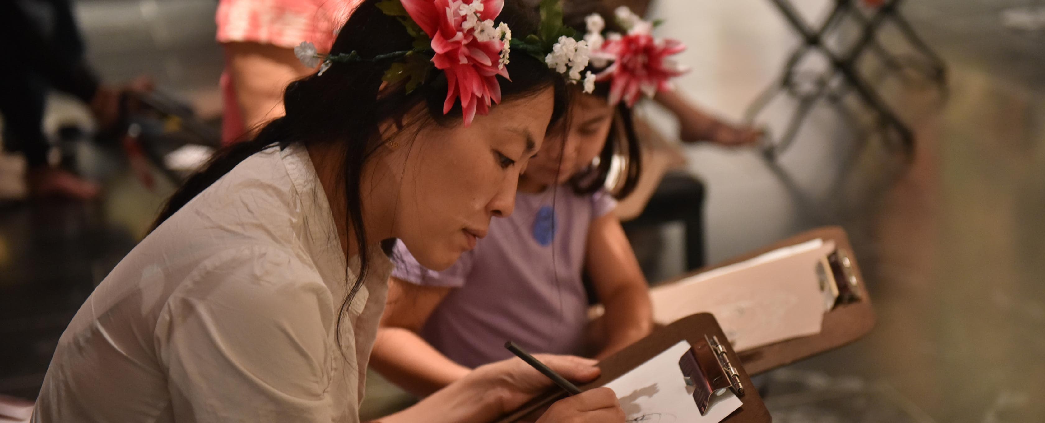 Mother and her daughter wearing flower crowns drawing in the galleries.