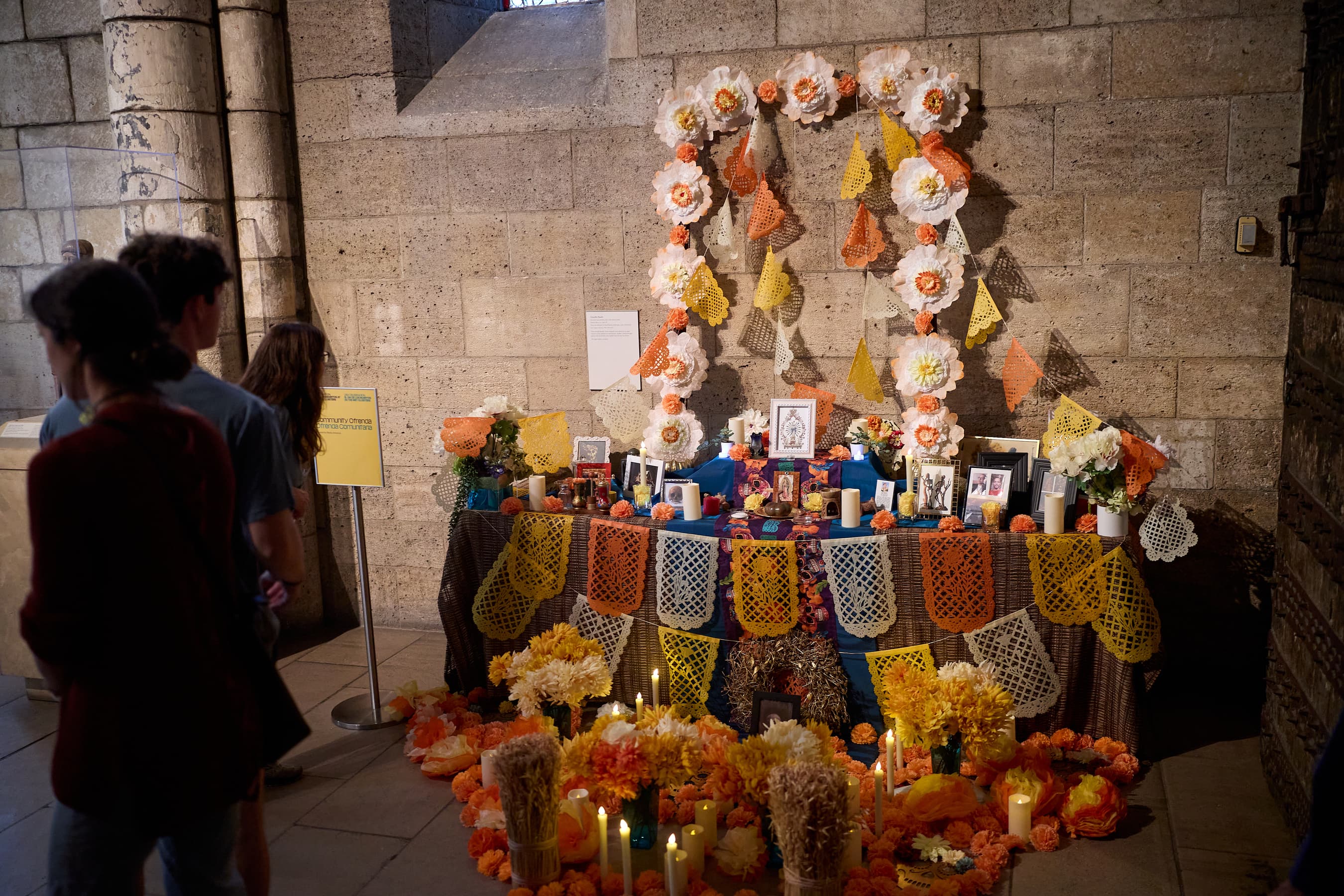 A colorful alter with flowers, candles, and pictures of loved ones