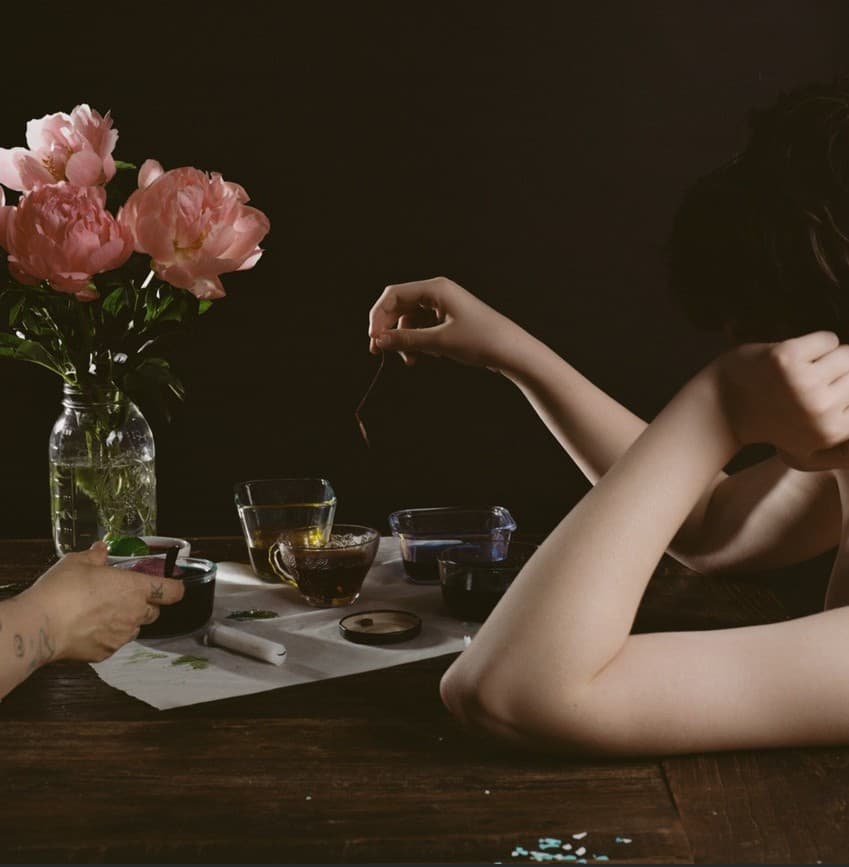 Arms and hands of two people on a table with flower vase and cups
